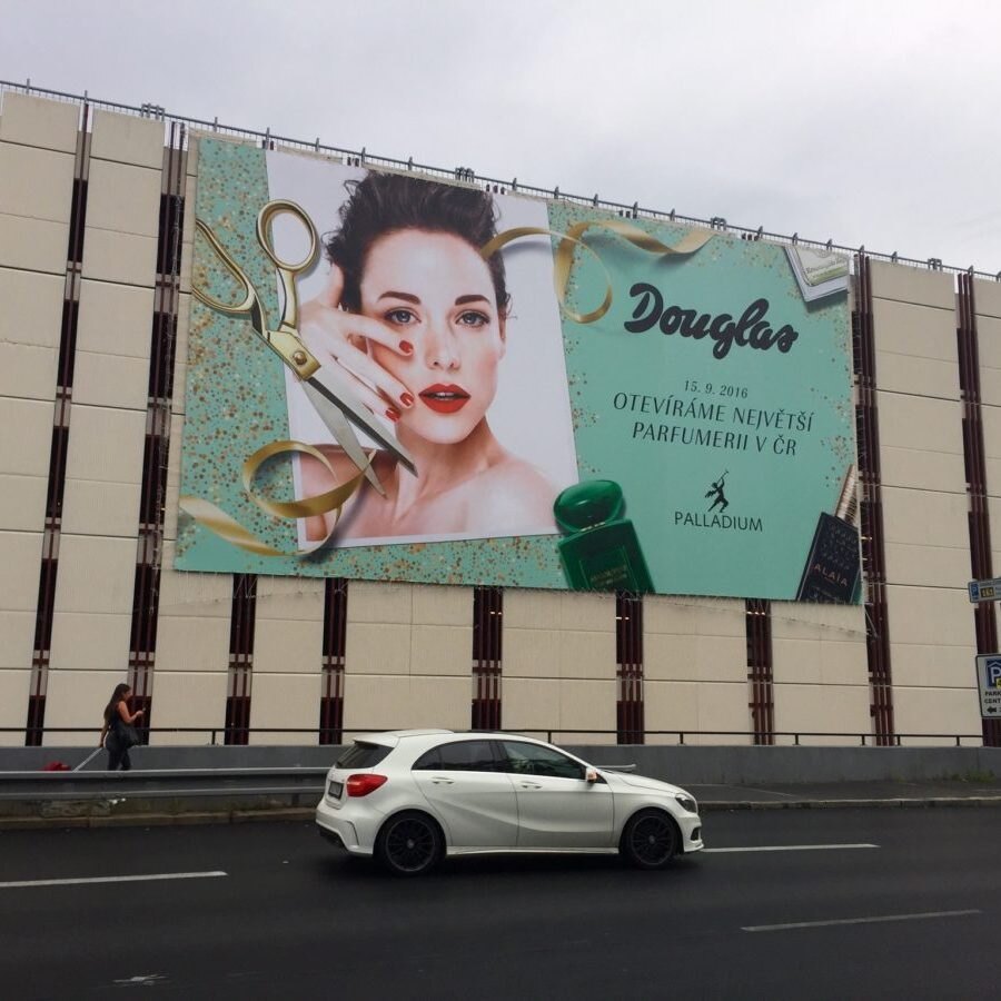 Veľká reklamná plocha na stene budovy s vizuálom parfumérie